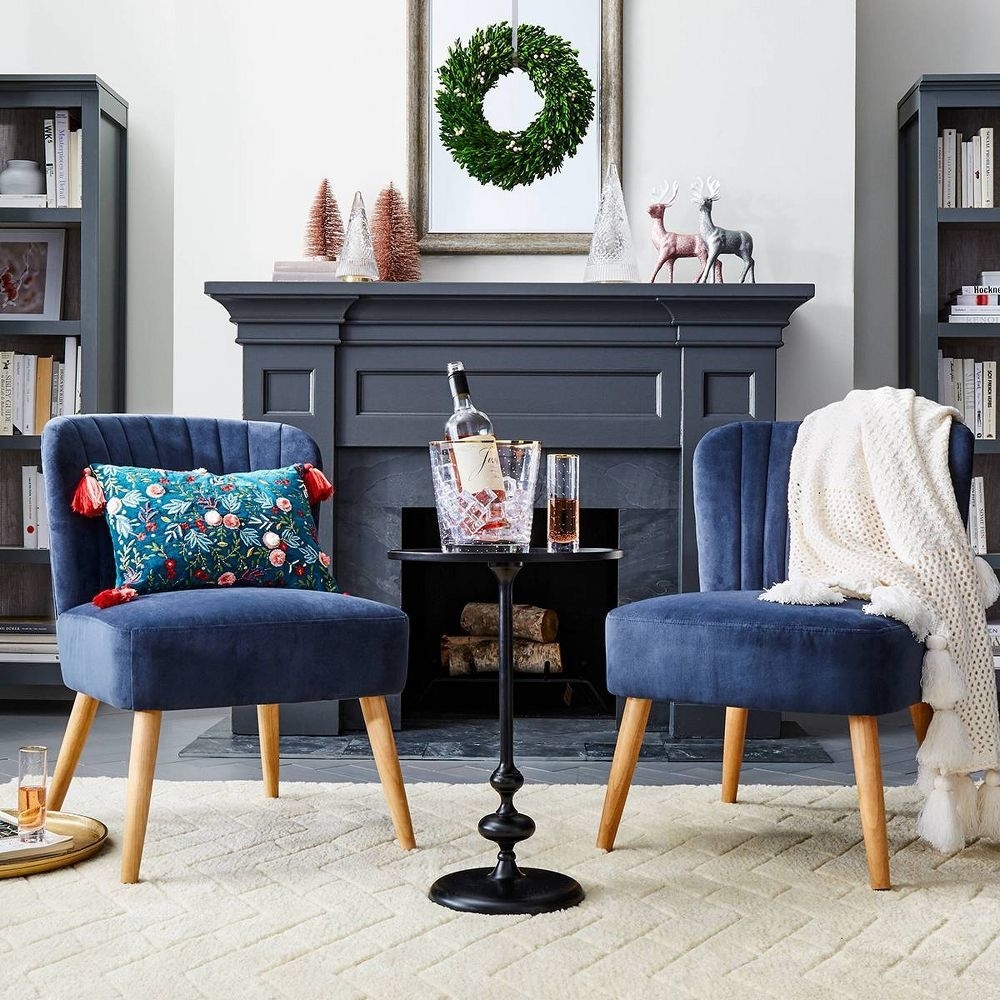 Two velvet accent chairs with floral patterns and a side table displaying glassware in a cozy living room setting