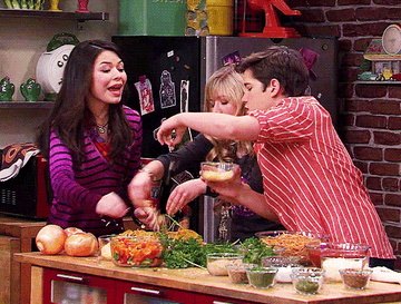Personajes de la serie iCarly, Carly, Sam y Freddie, peleando juguetonamente con comida en una cocina