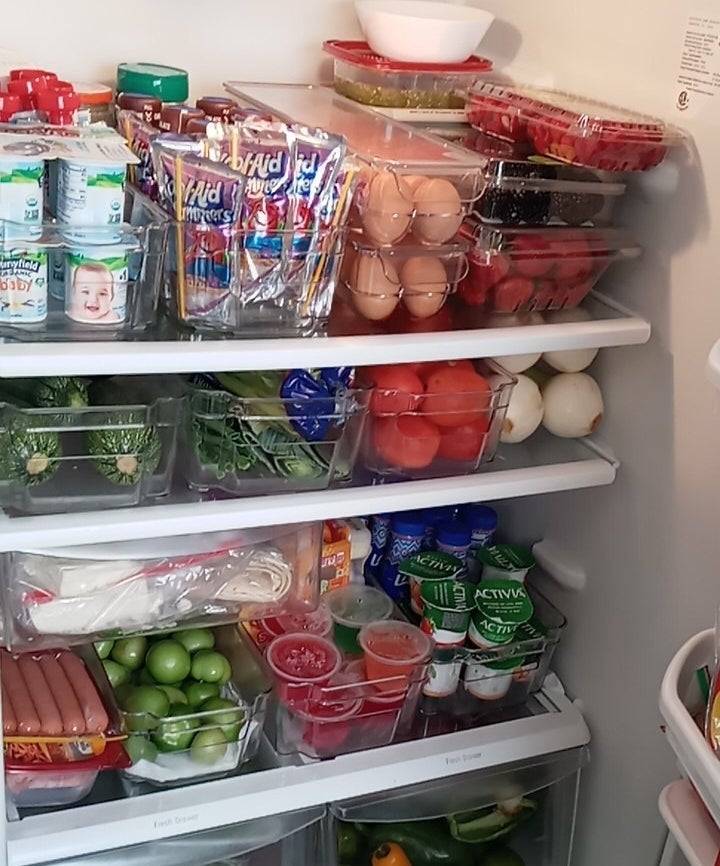 a reviewer photo of a well-stocked refrigerator with various food items such as eggs, dairy products, and fresh produce, showcasing an example of grocery organization