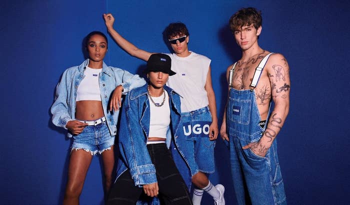 Four models in denim wear pose against a blue backdrop, one with a bucket hat