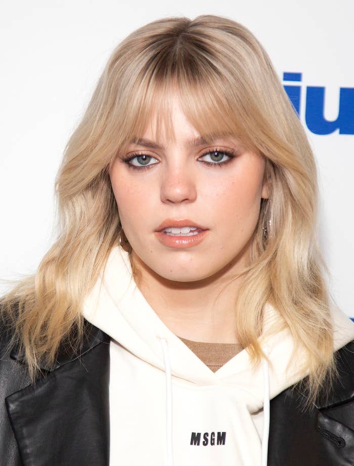 Reneé Rapp in a leather jacket and graphic hoodie attends an event