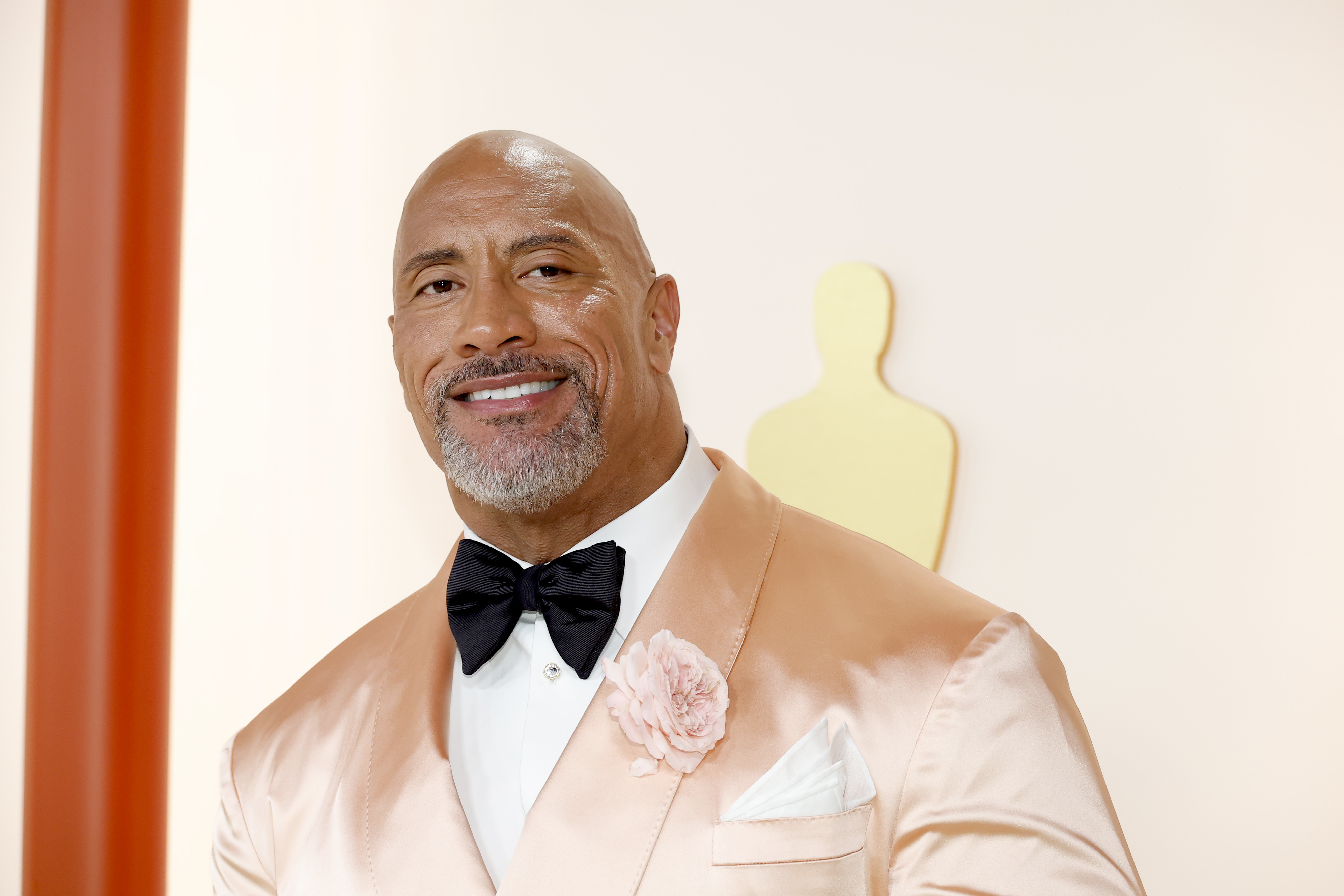 Dwayne Johnson wearing a pastel tuxedo with a bow tie and floral lapel pin