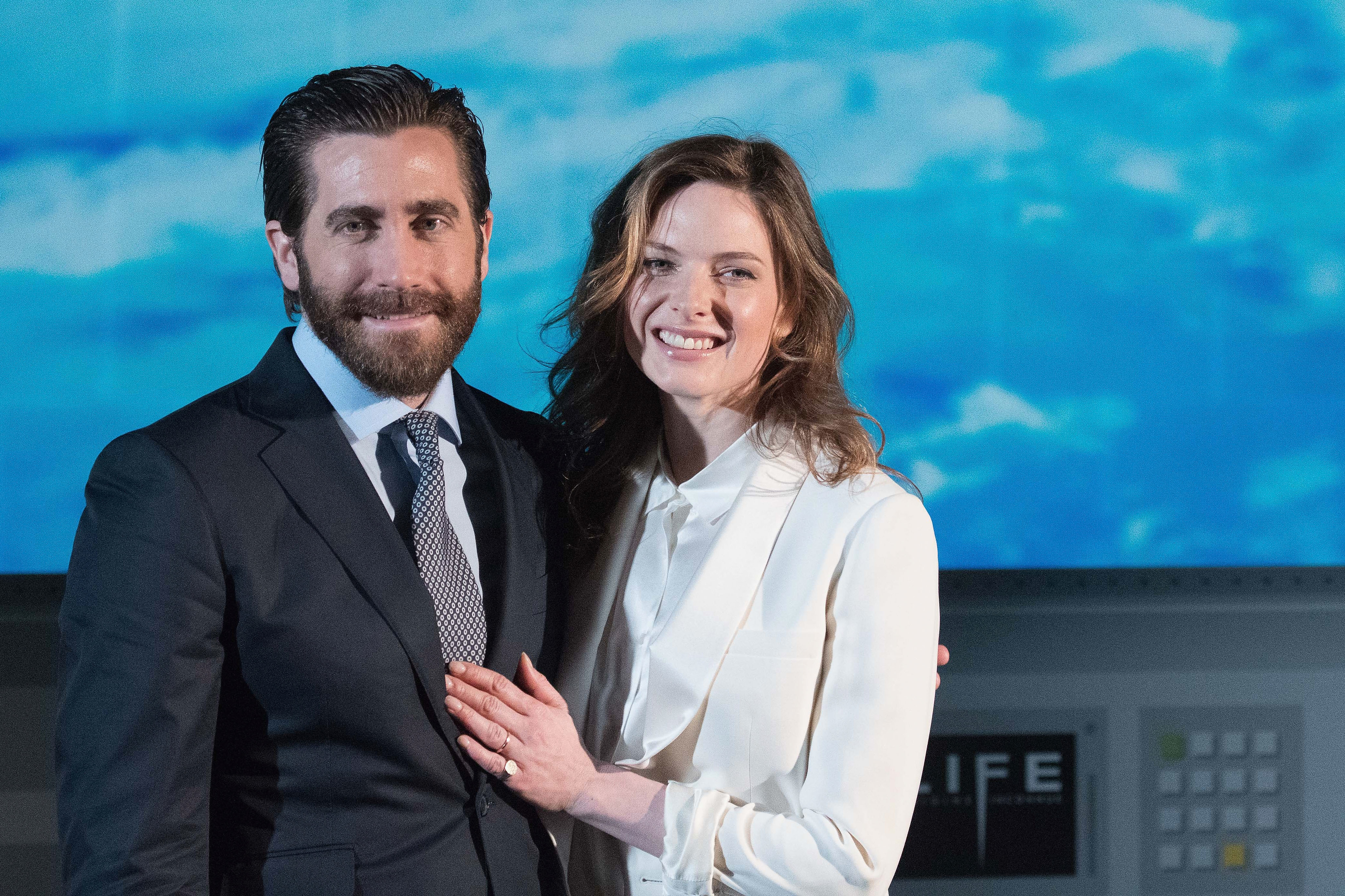 Jake Gyllenhaal and Rebecca Ferguson smiling, posing in semiformal attire for an event