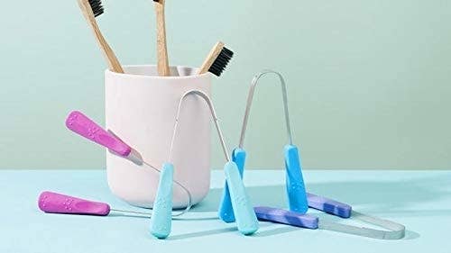 Assorted dental hygiene products including toothbrushes and tongue cleaners on a flat surface