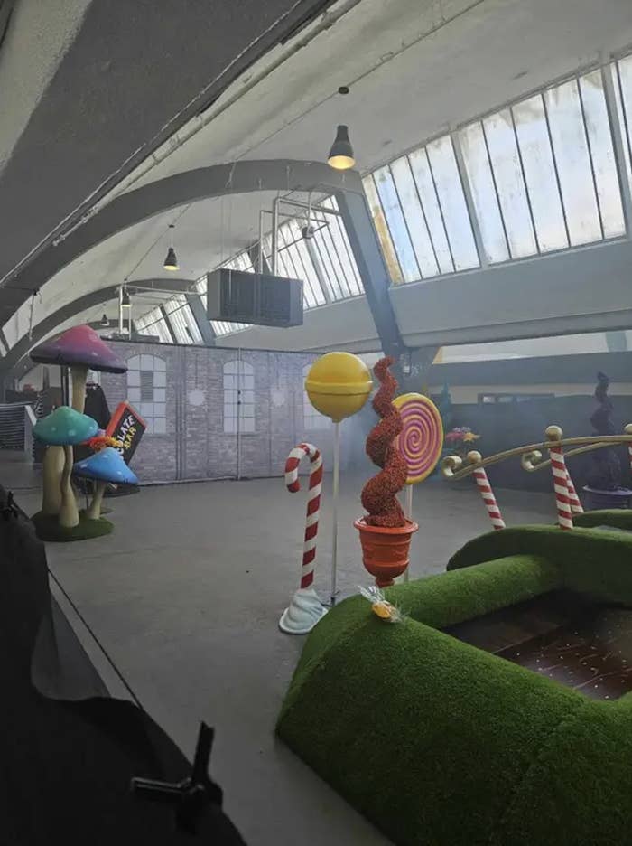 A supposedly whimsical indoor space with oversized candy decorations and mushroom seats, resembling a scene from a fantasy