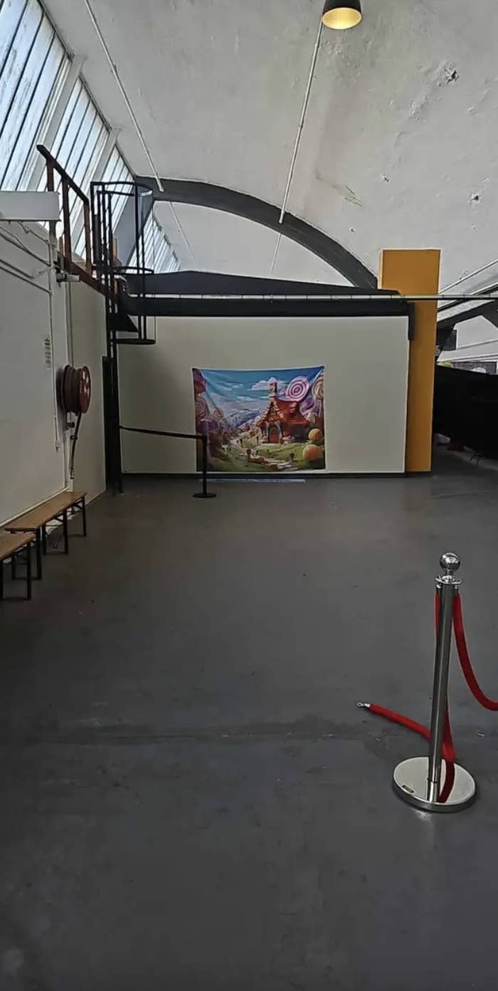 A small canvas displaying artwork on a wall in a large empty warehouse space
