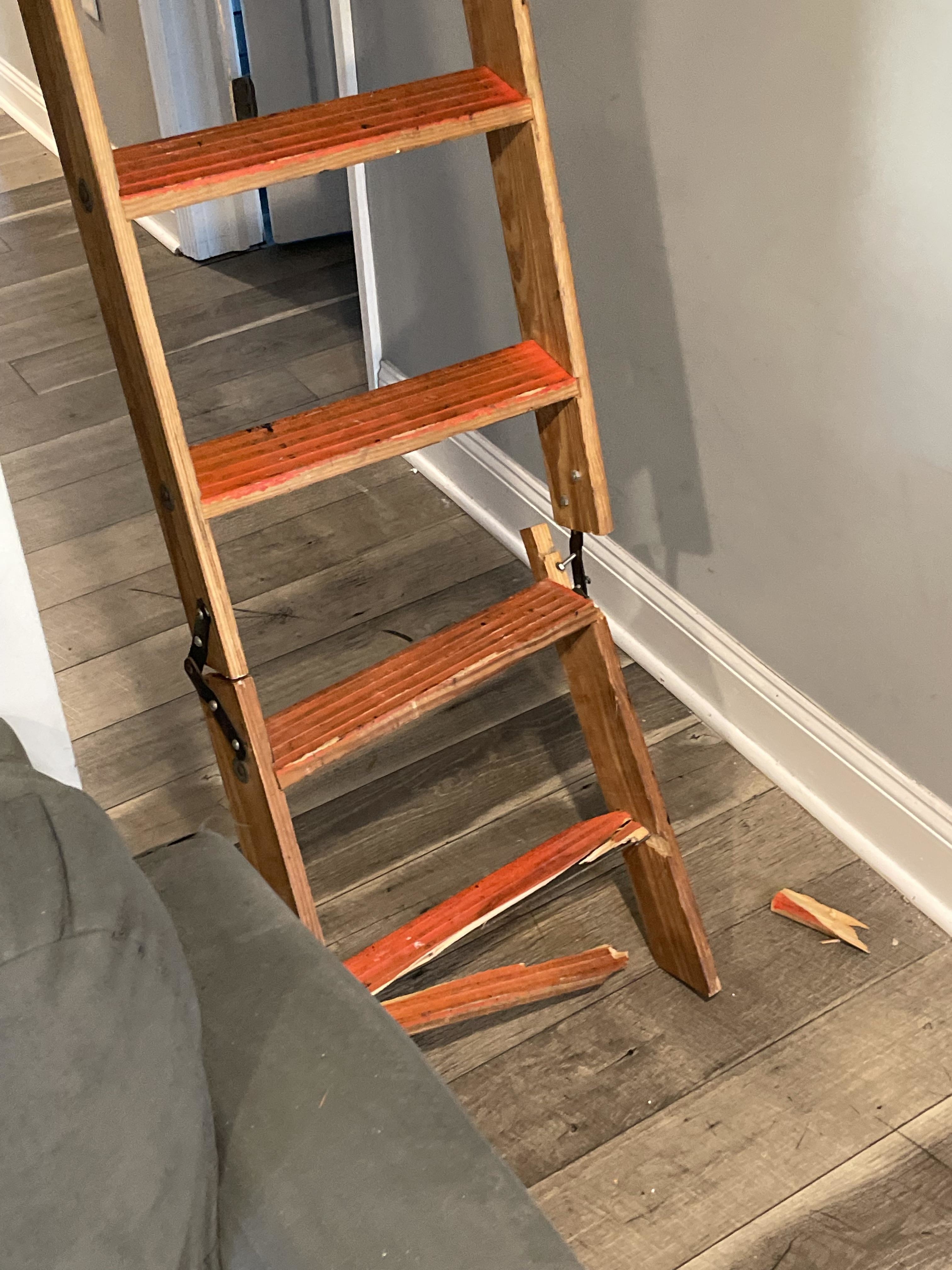Wooden step ladder with a broken step, pieces on the floor