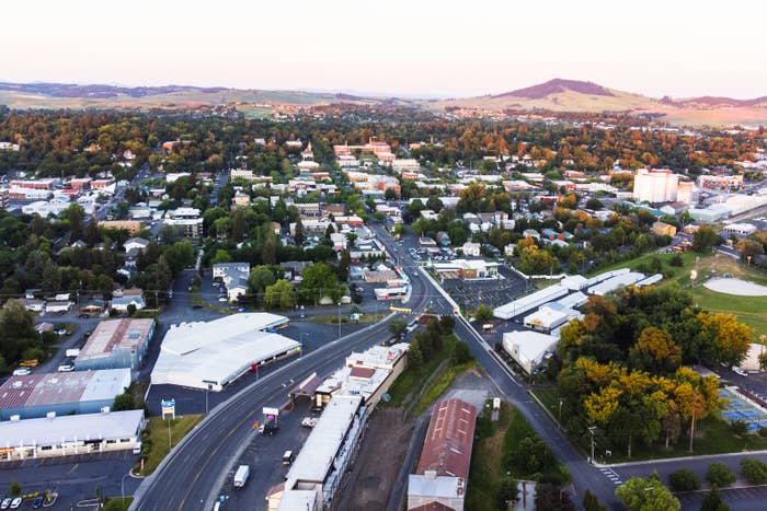 Aerial view of a small town with buildings, roads, and greenery during twilight