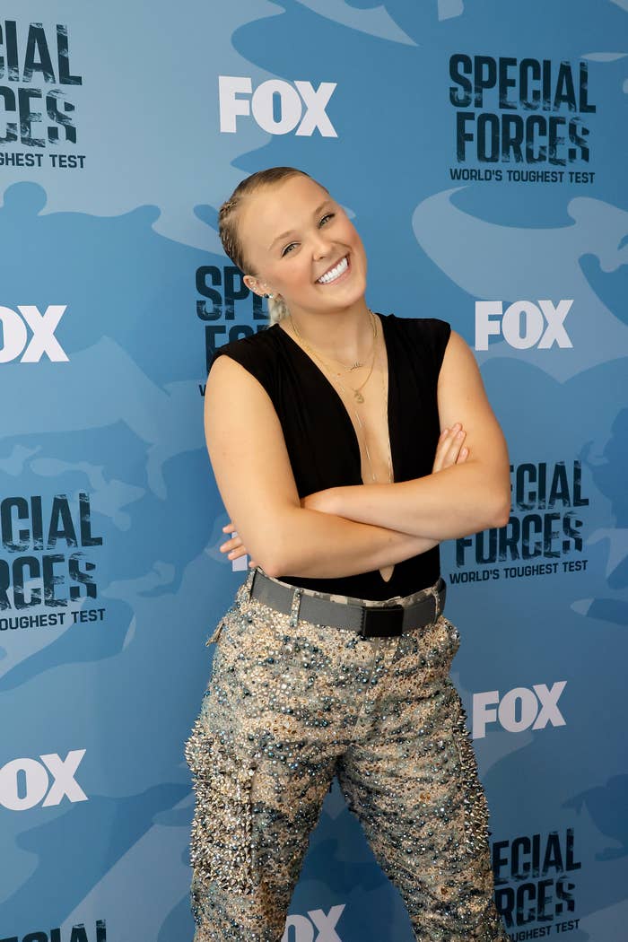 JoJo in top and sequined pants posing with her arms crossed at FOX event