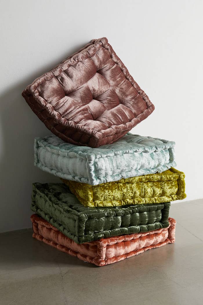 Stack of five plush velvet floor pillows in various shades