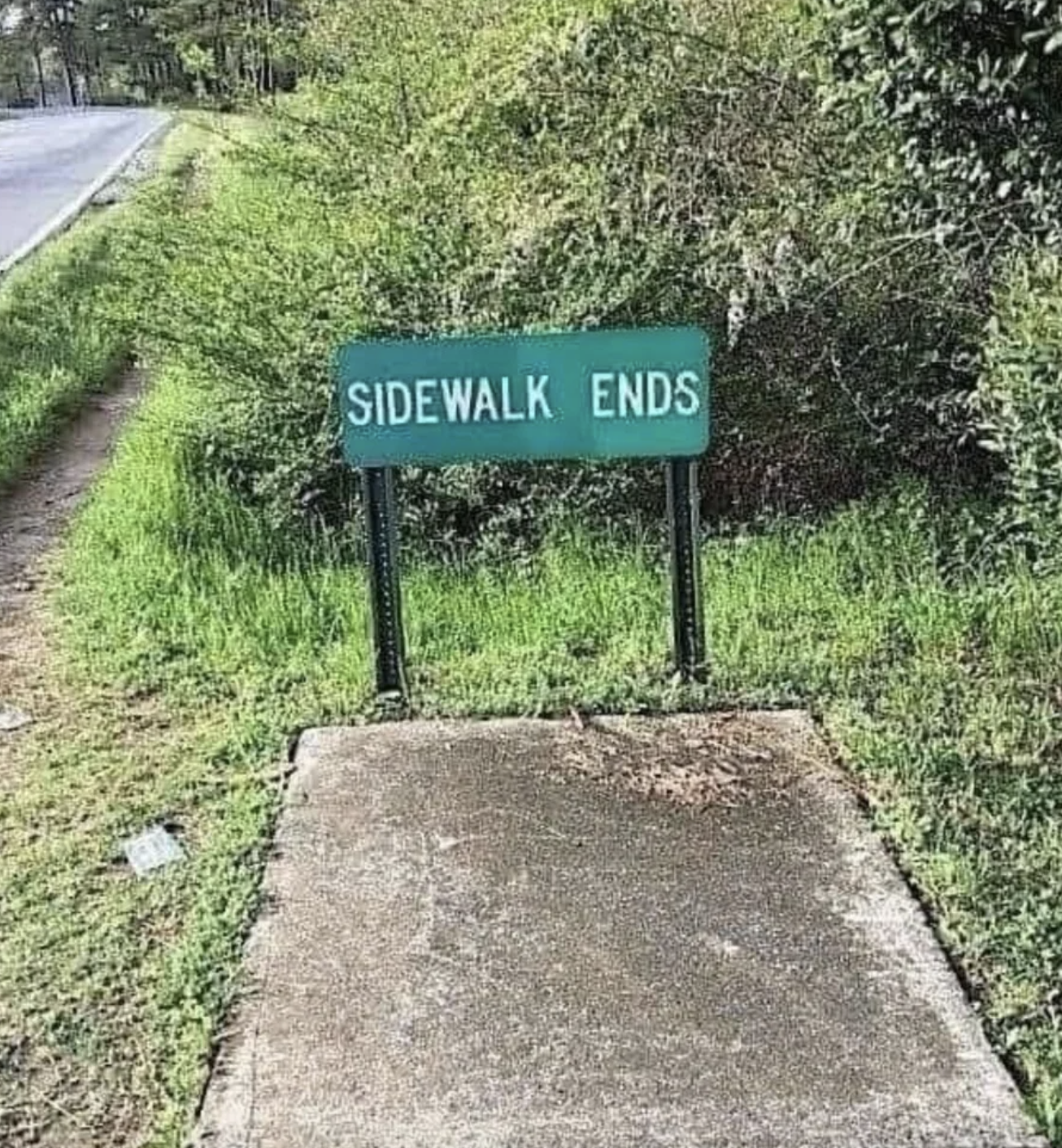 Sign reads &quot;SIDEWALK ENDS&quot; where a concrete sidewalk meets grass