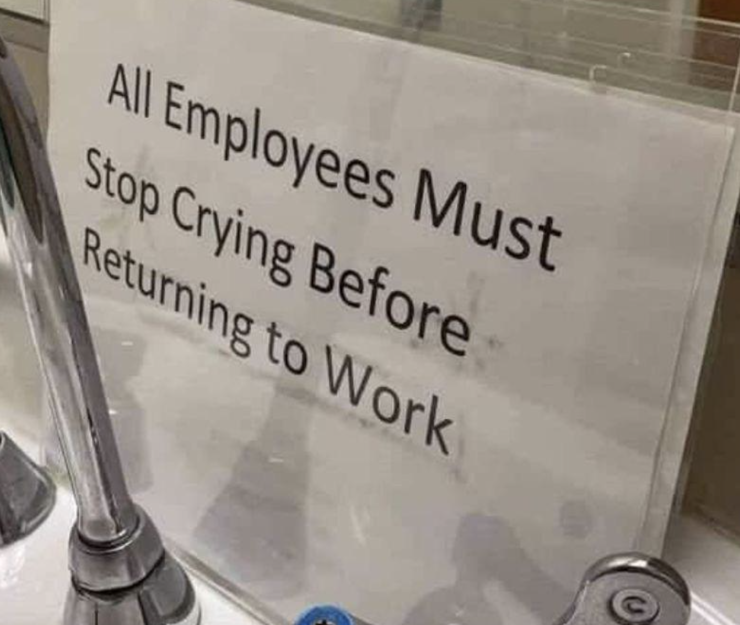 Sign reads &quot;All Employees Must Stop Crying Before Returning to Work&quot; displayed near a sink