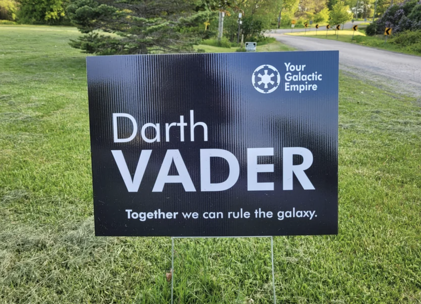 Sign with &quot;Darth Vader - Together we can rule the galaxy&quot; alongside the logo &quot;Your Galactic Empire&quot; on grass