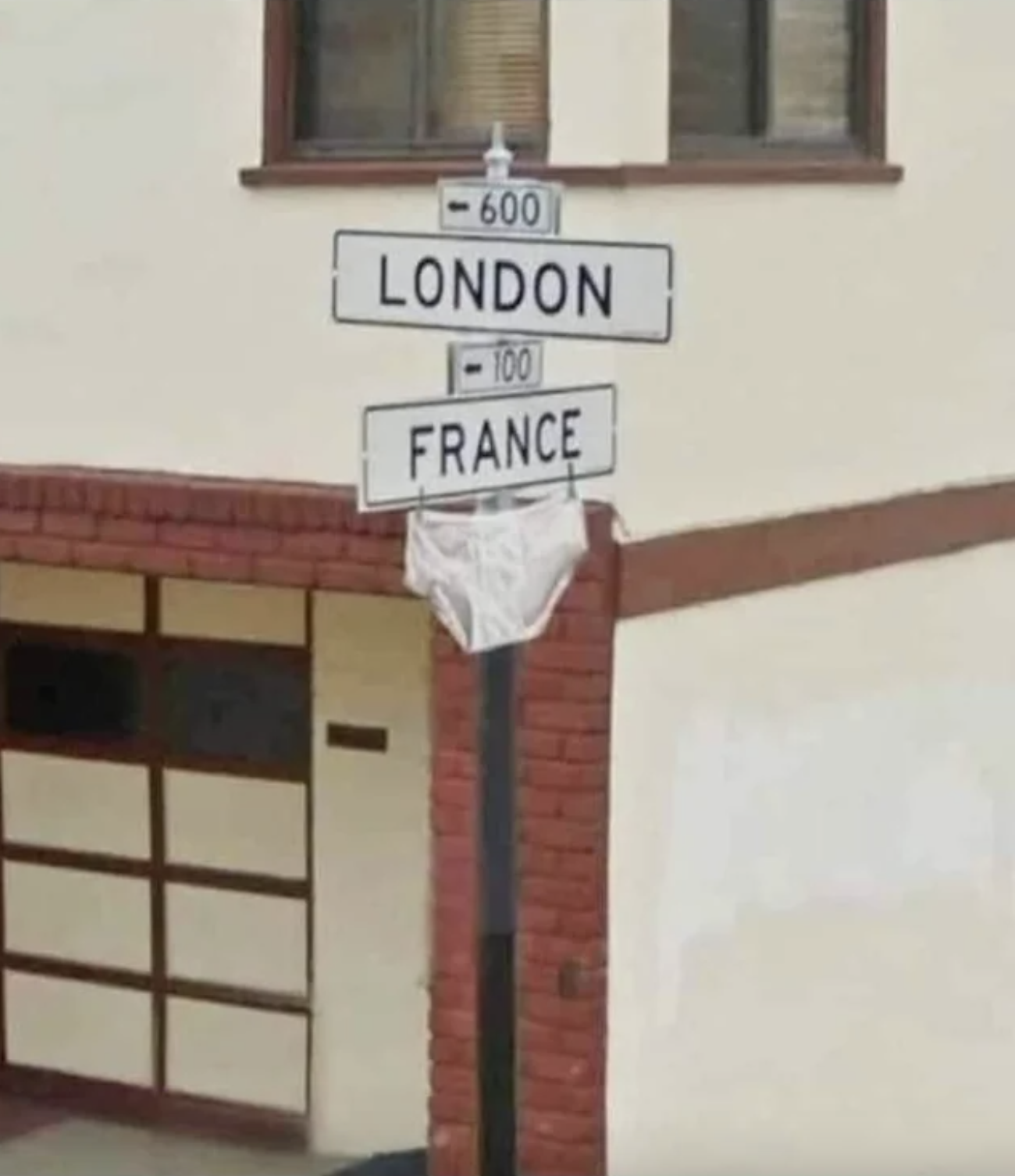 Directional signs pointing to &quot;LONDON&quot; and &quot;FRANCE&quot; with undergarments hanging on one sign