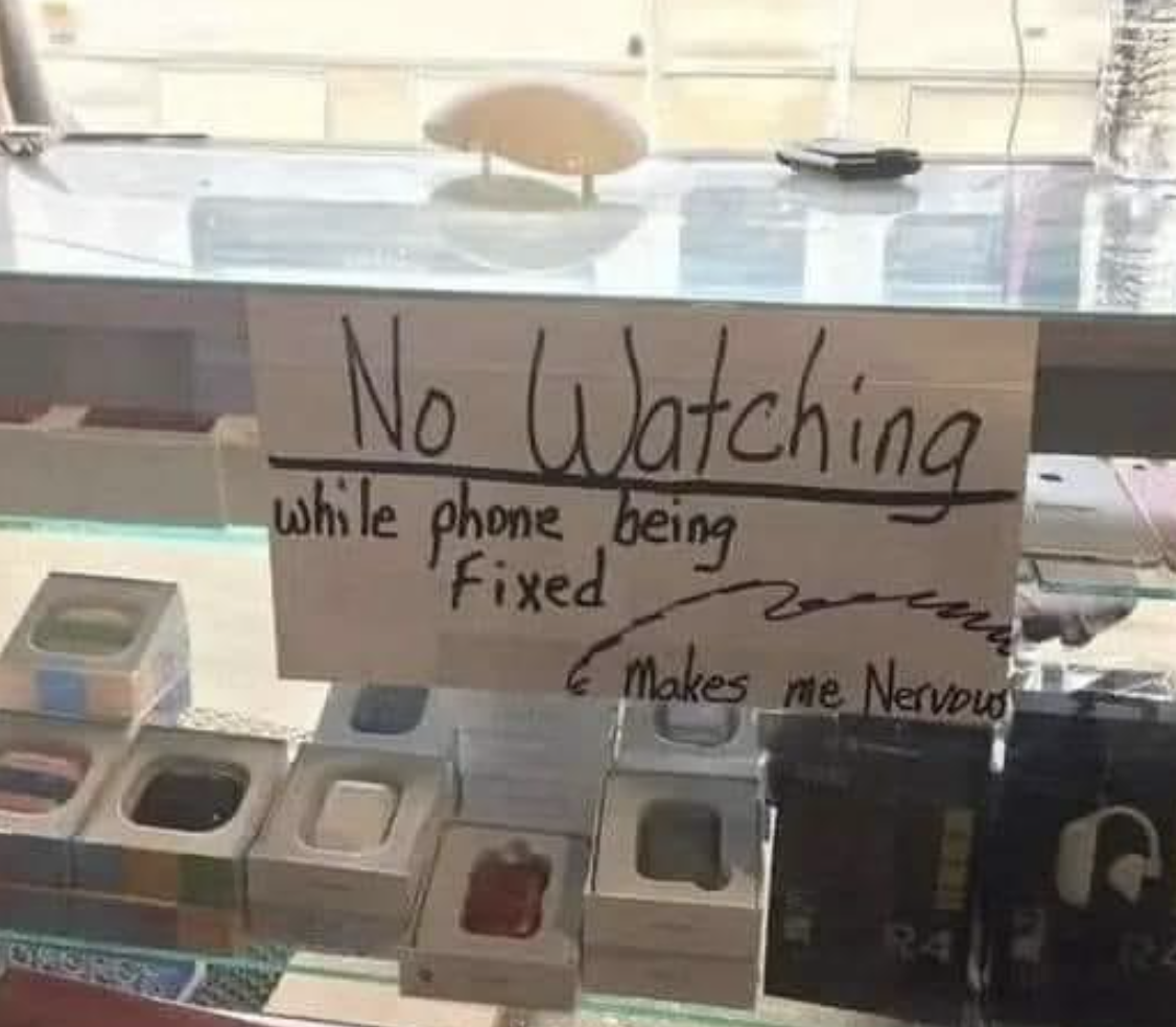 Sign on store counter reads &quot;No Watching while phone being fixed, Makes me nervous,&quot; prohibiting observation of repairs