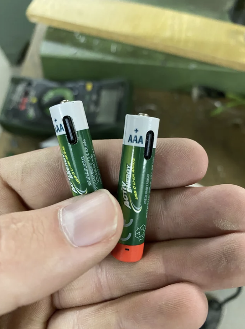 Hand holding a AA and a AAA battery for comparison