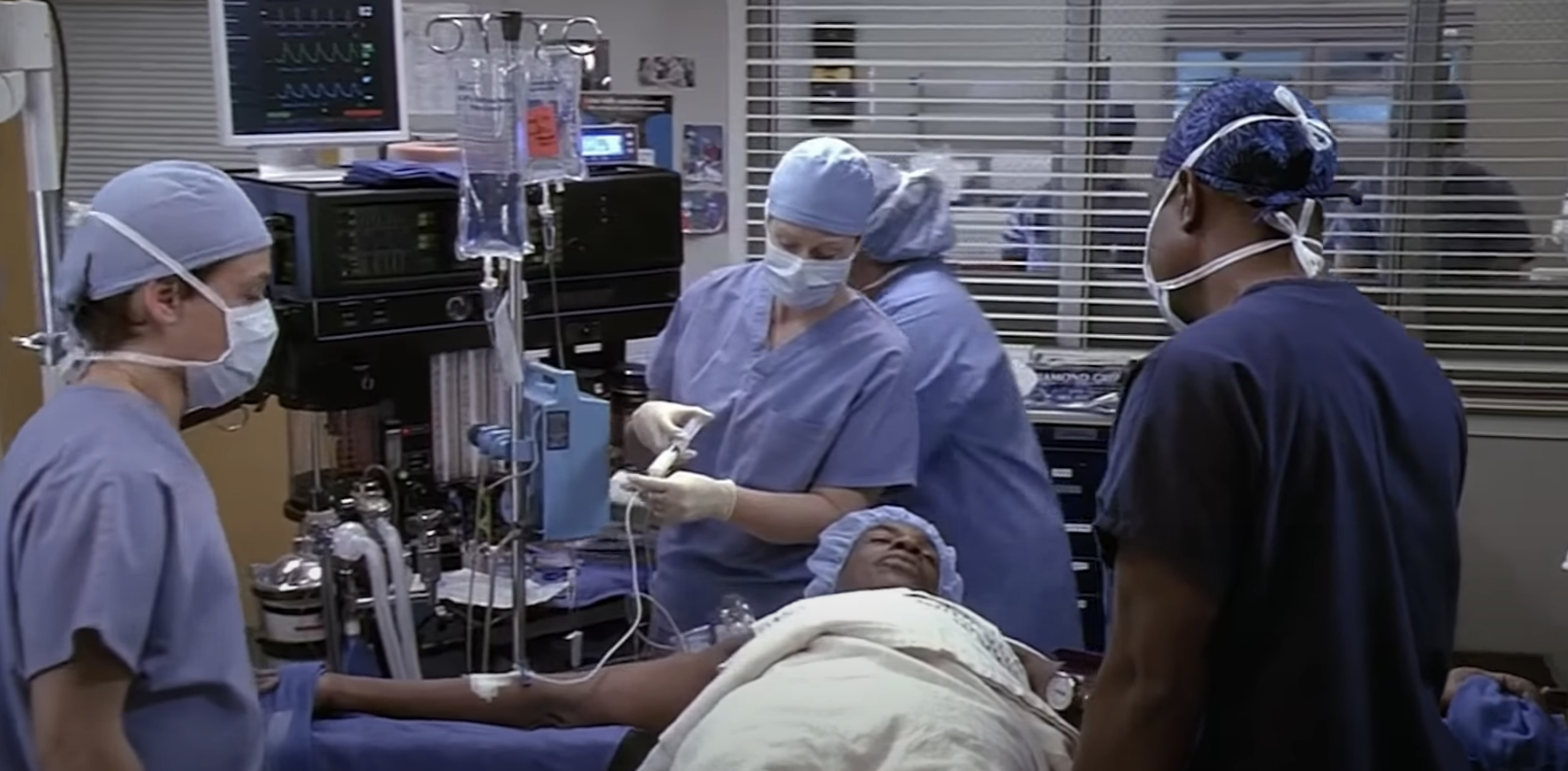 Medical team in scrubs performing surgery on a patient in an operating room