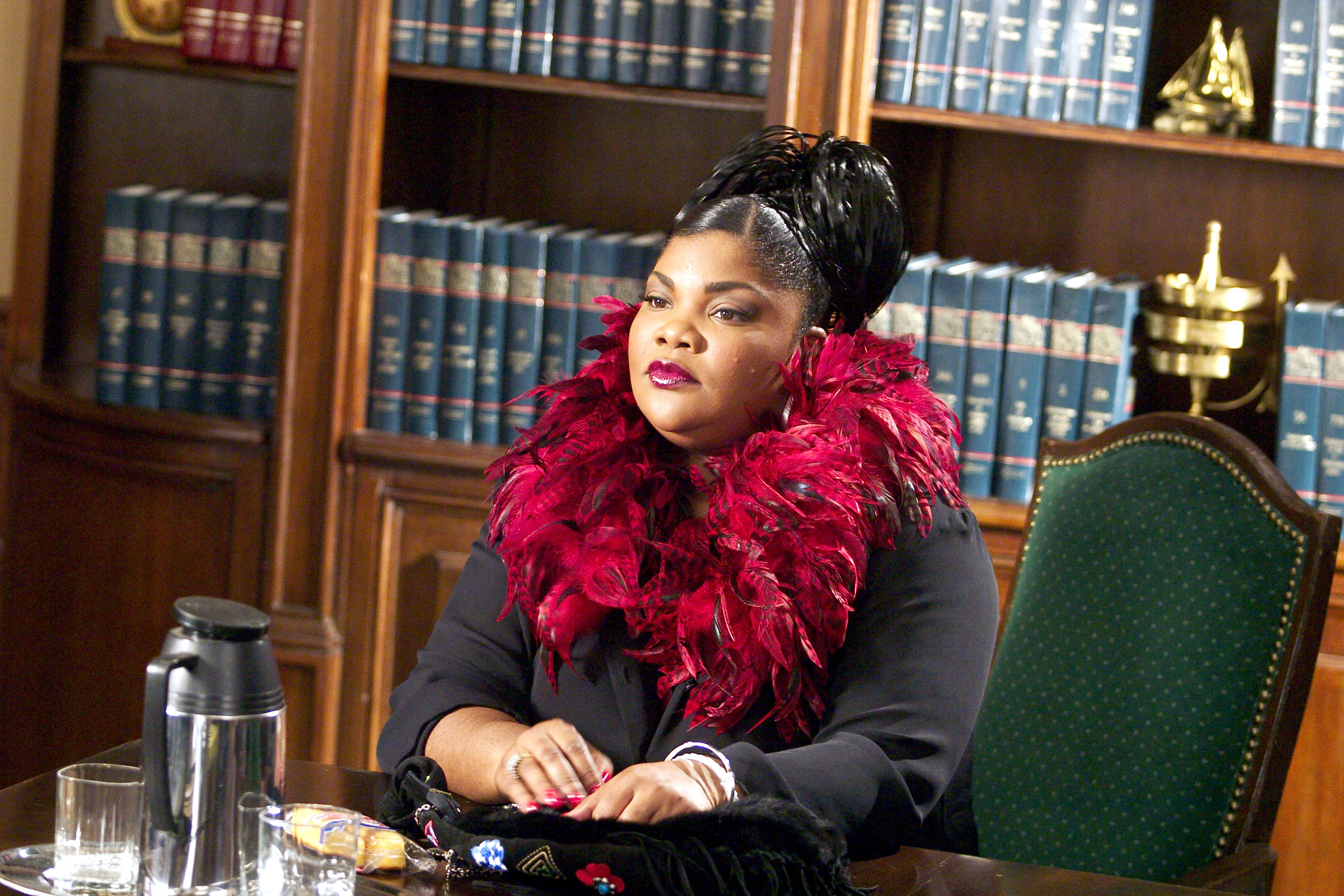 Mo&#x27;Nique in a law office scene, wearing a dramatic feather boa