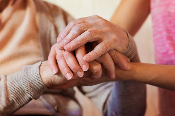 Two people holding hands in a caring gesture, signifying comfort or support