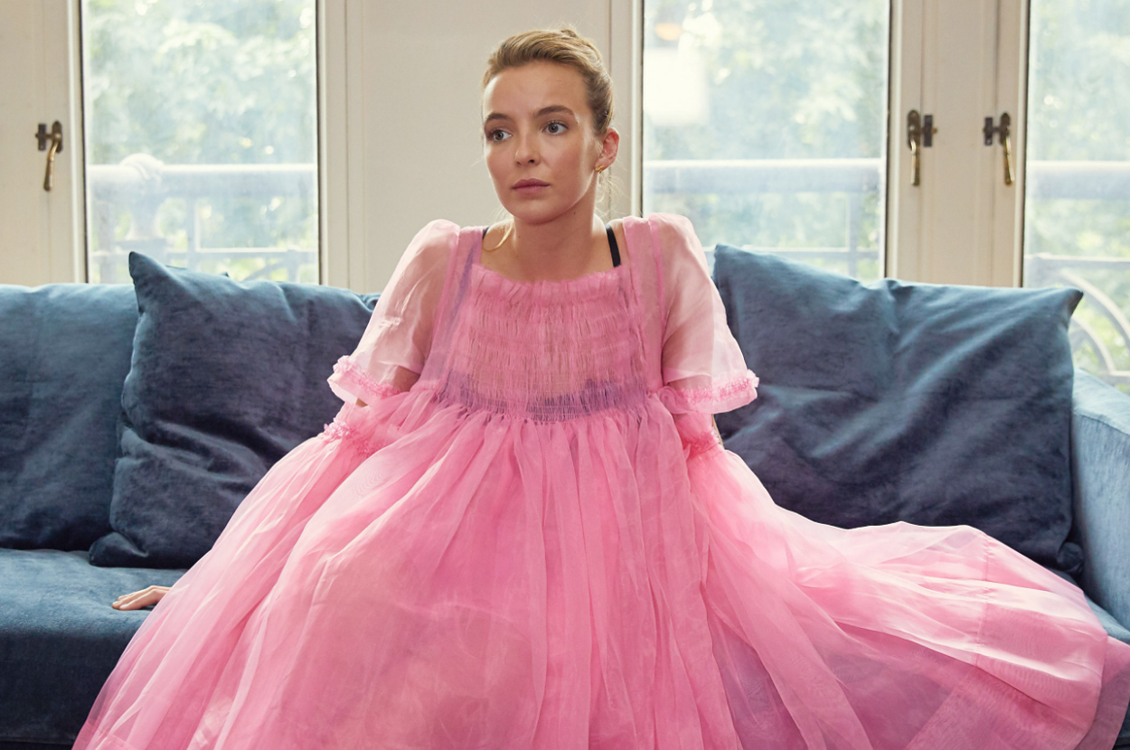 Jodie Comer sitting on a couch in a fabulous dress as Villanelle on Killing Eve