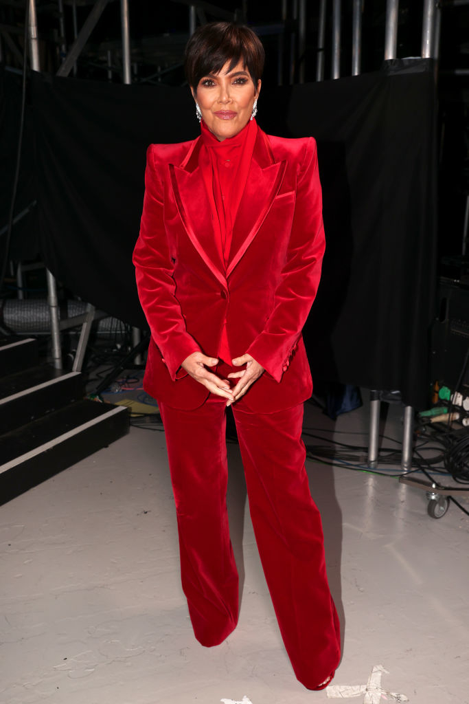 Kris Jenner in a velvet suit with a blazer and trousers, posing backstage