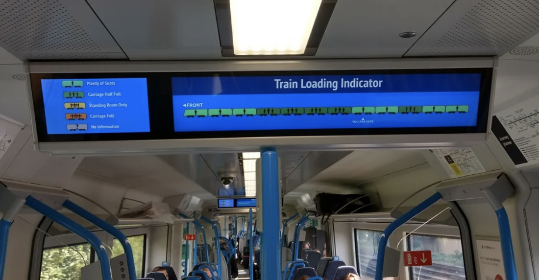 Digital display showing train loading indicator with seat availability in each carriage