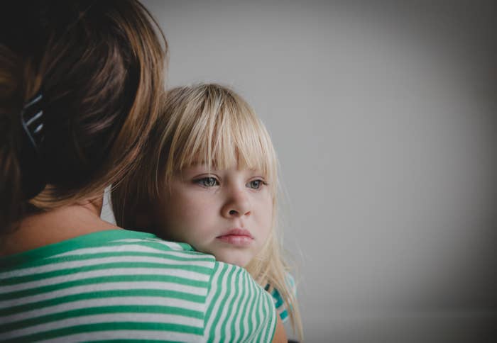 Woman holding a child with a pensive expression