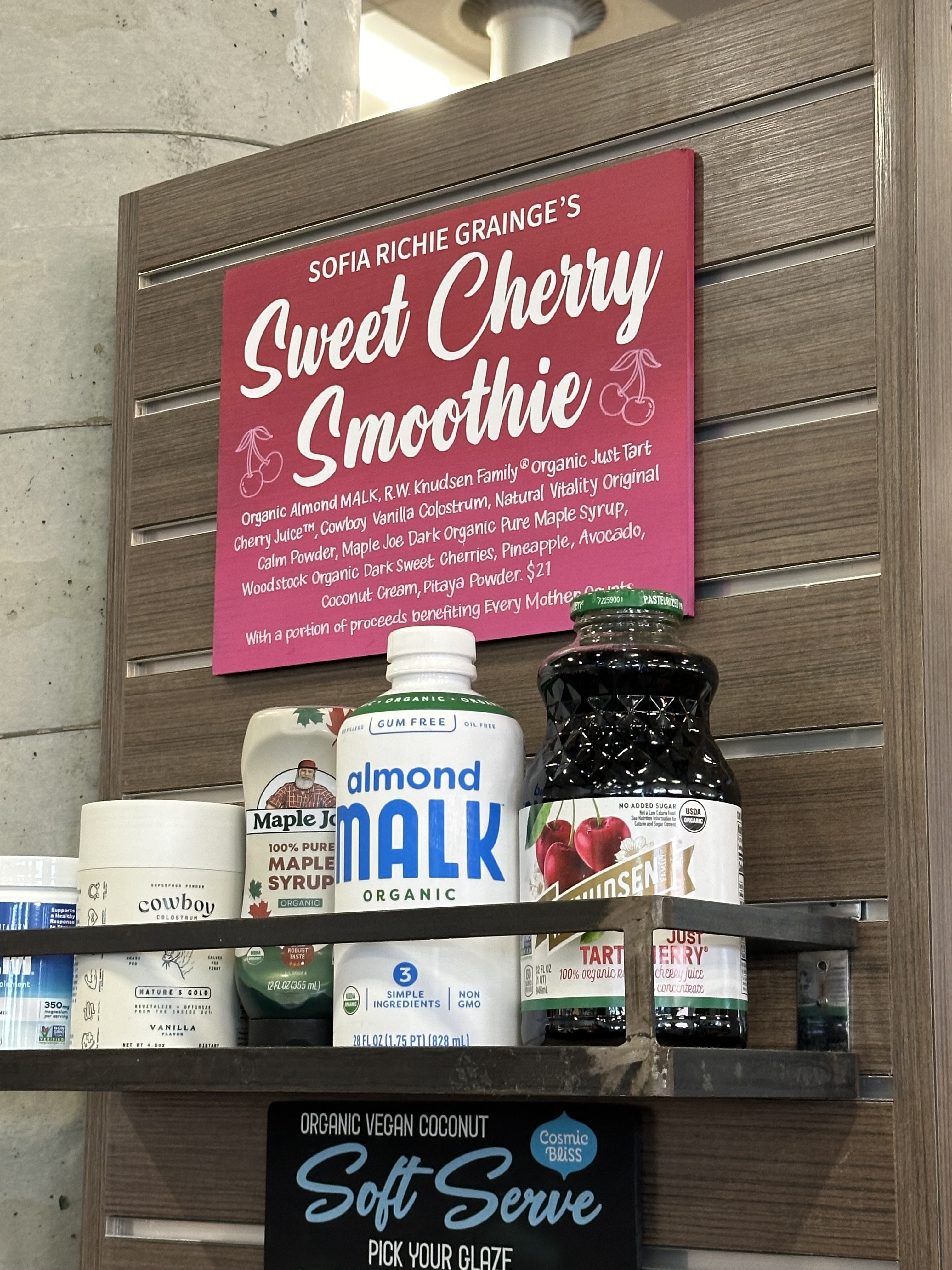 Shelf with various organic food products under a pink sign reading &quot;SOFIA RICHIE GRAINGE&#x27;S Sweet Smoothie Cherry Smoothie.&quot;