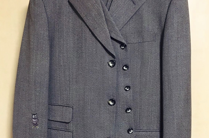 灰色のダブルブレストスーツジャケット、ボタンとポケットが特徴