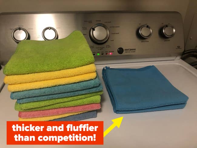 reviewer's stack of microfiber cleaning cloths next to stack of competitor's