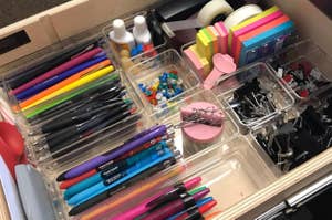 a desk drawer with organization trays full of office supplies