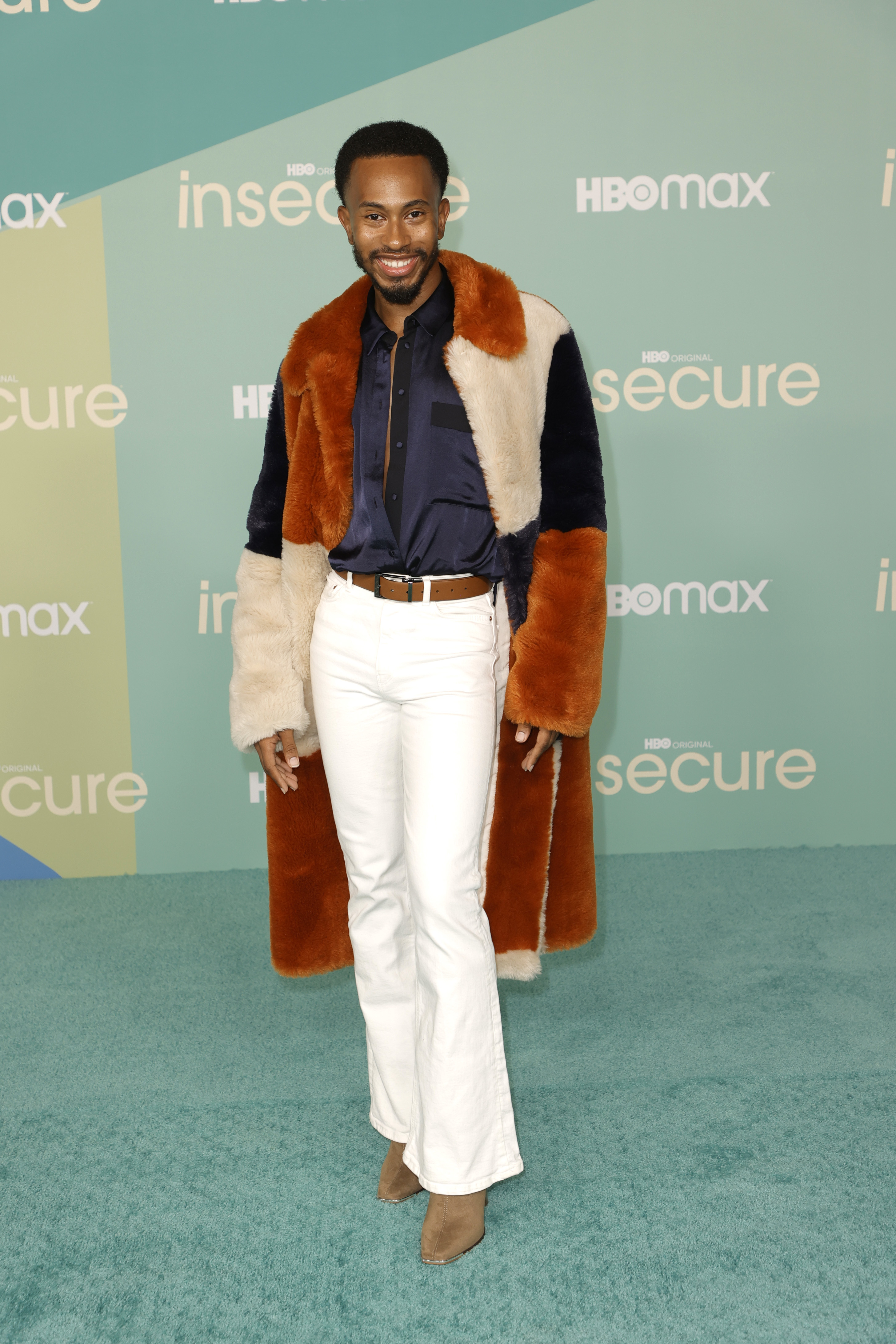 Kalen Allen smiles for the camera at a media event while wearing a shearling coat