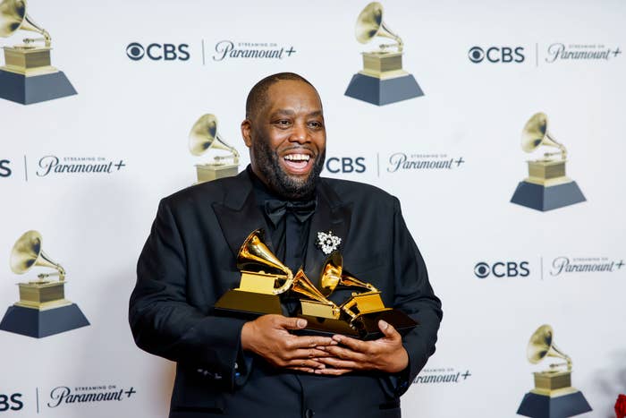 Killer Mike smiling and holding three Grammys