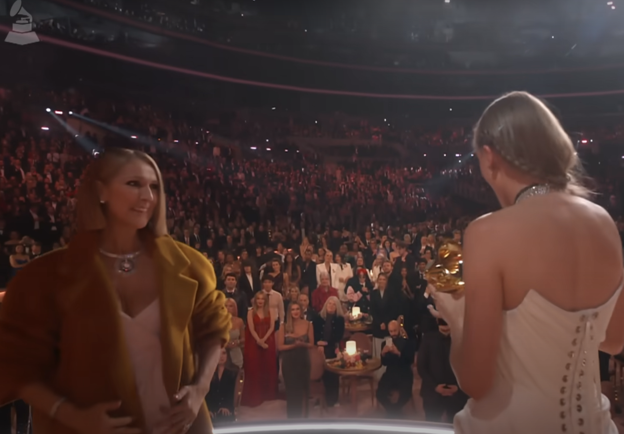 Close-up of Taylor onstage holding her Grammy as Céline smiles at her