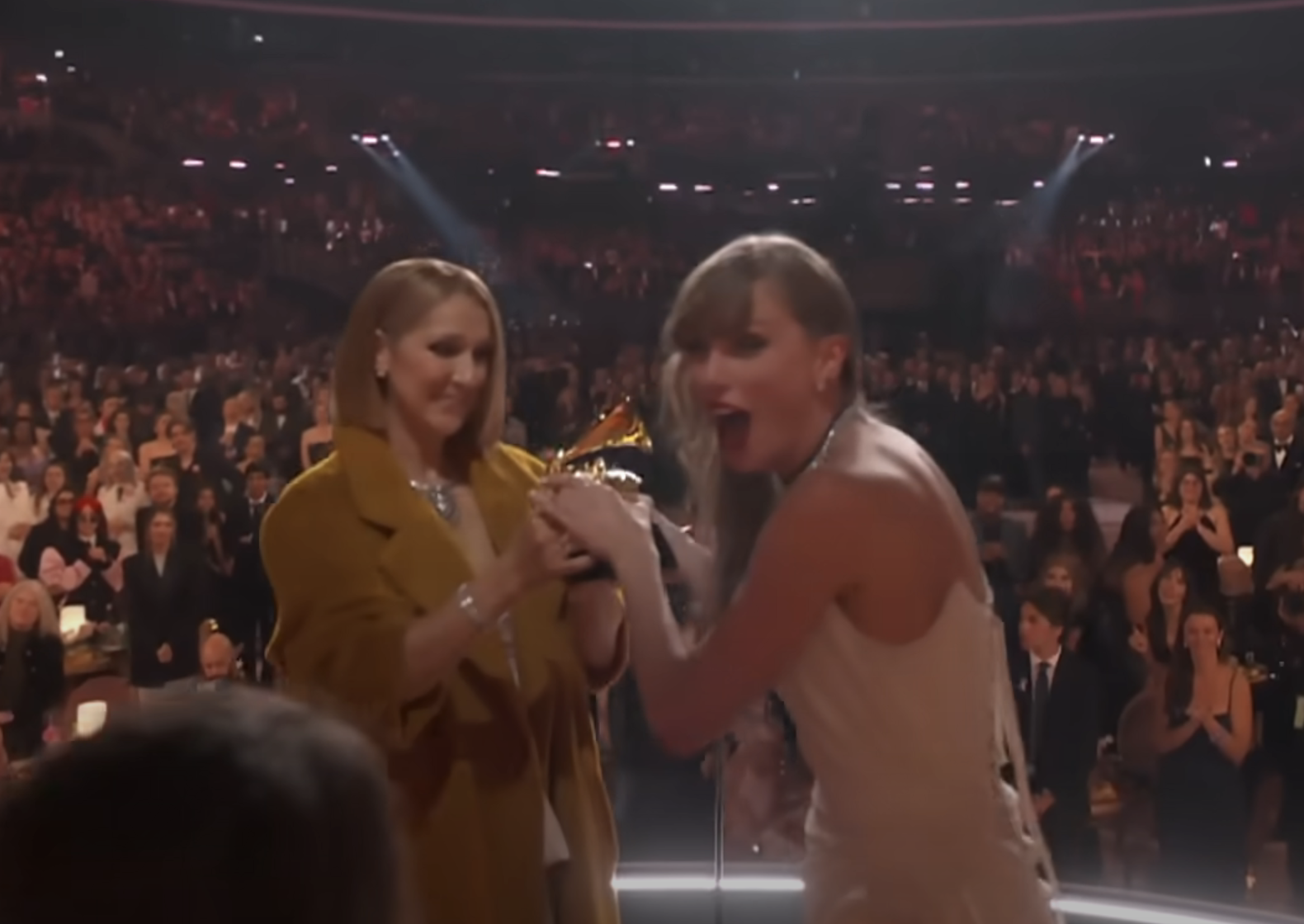 Close-up of Taylor onstage taking her Grammy from Céline without looking at her