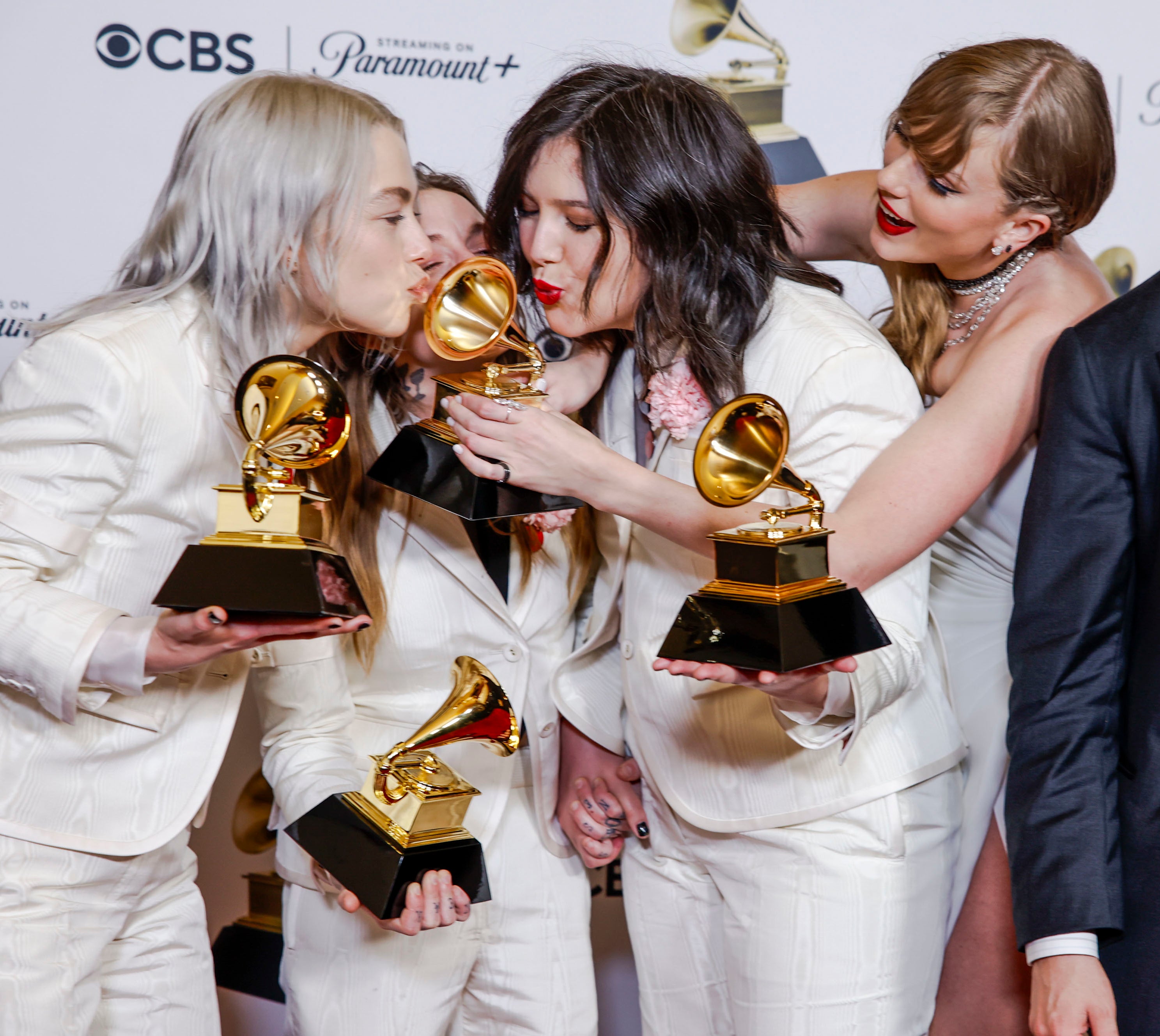 Boygenius holding their Grammys with Taylor Swift helping