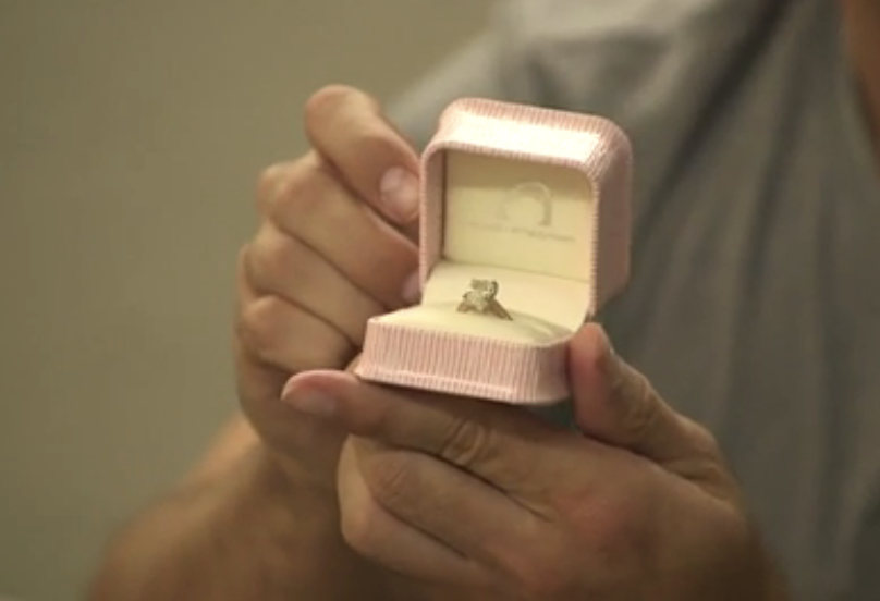 a person holding out an engagement ring in a box