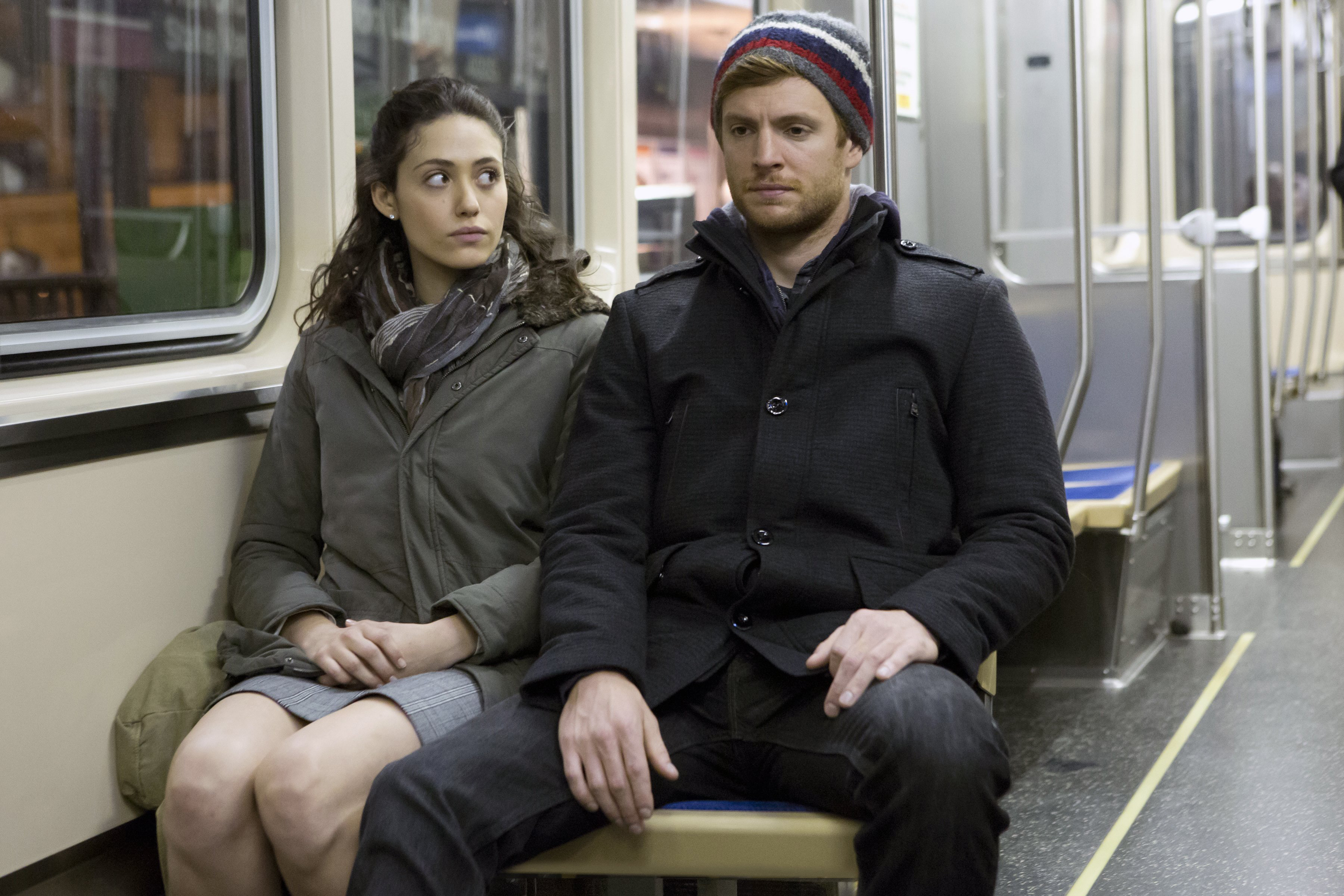 Emmy Rossum and Nick Gehlfuss sitting on a train
