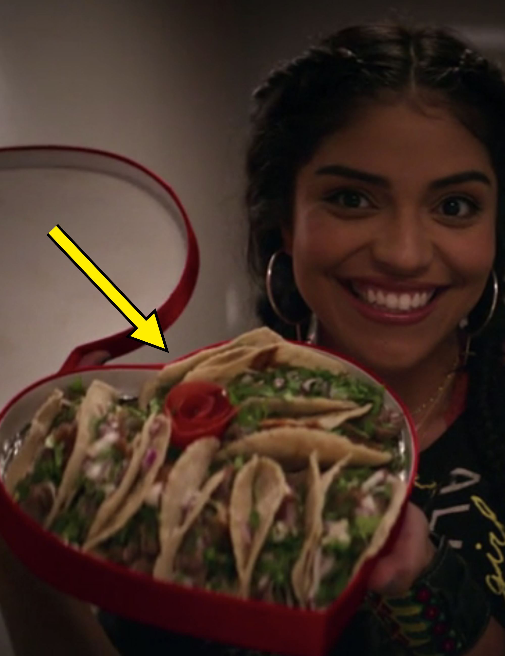 A woman holding up a heart-shaped box with tacos inside