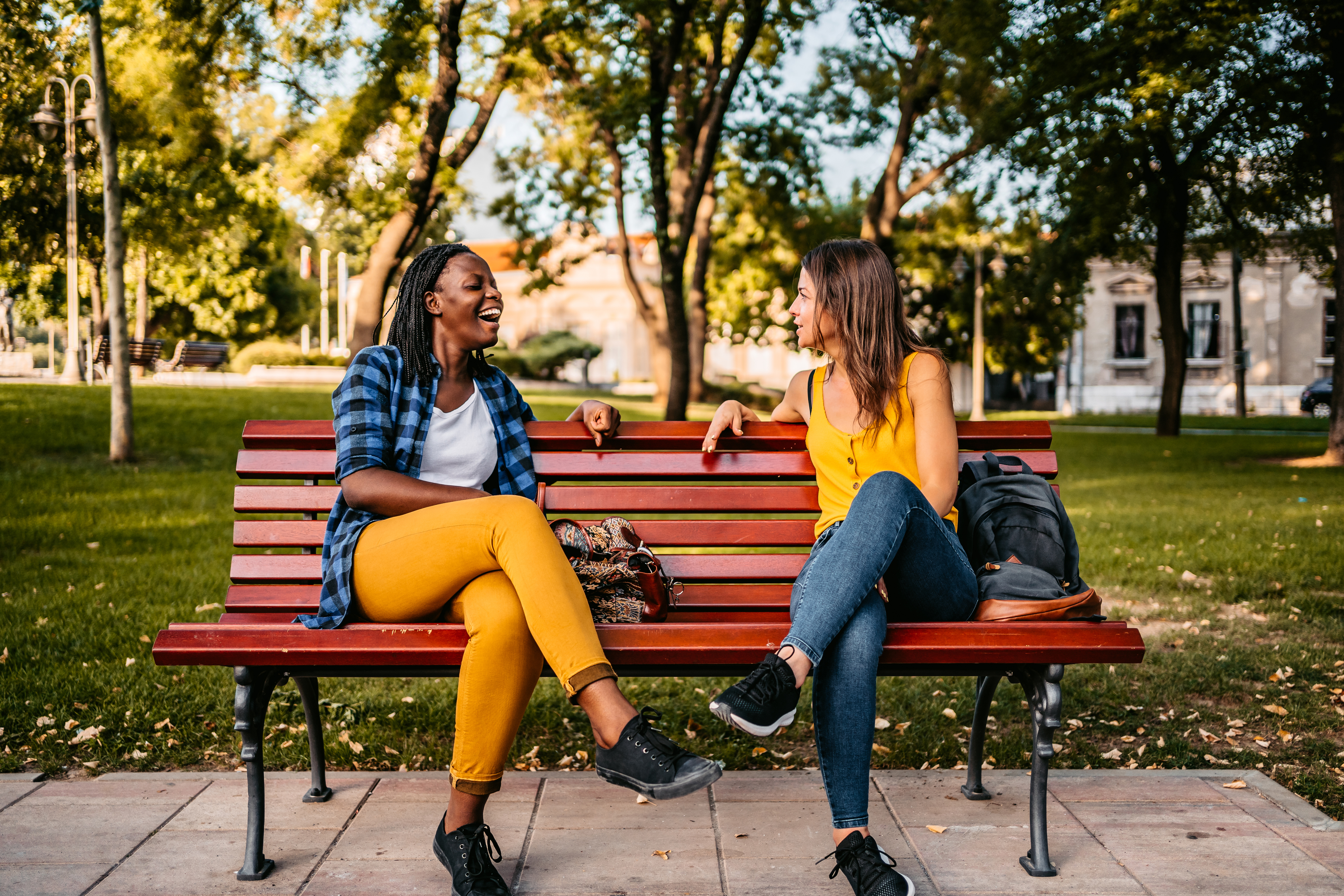 Two friends sitting on a park bench, talking and smiling