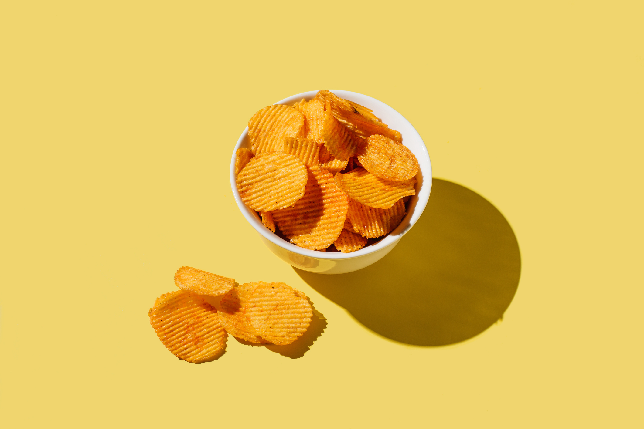 Plate of potato chips on yellow background