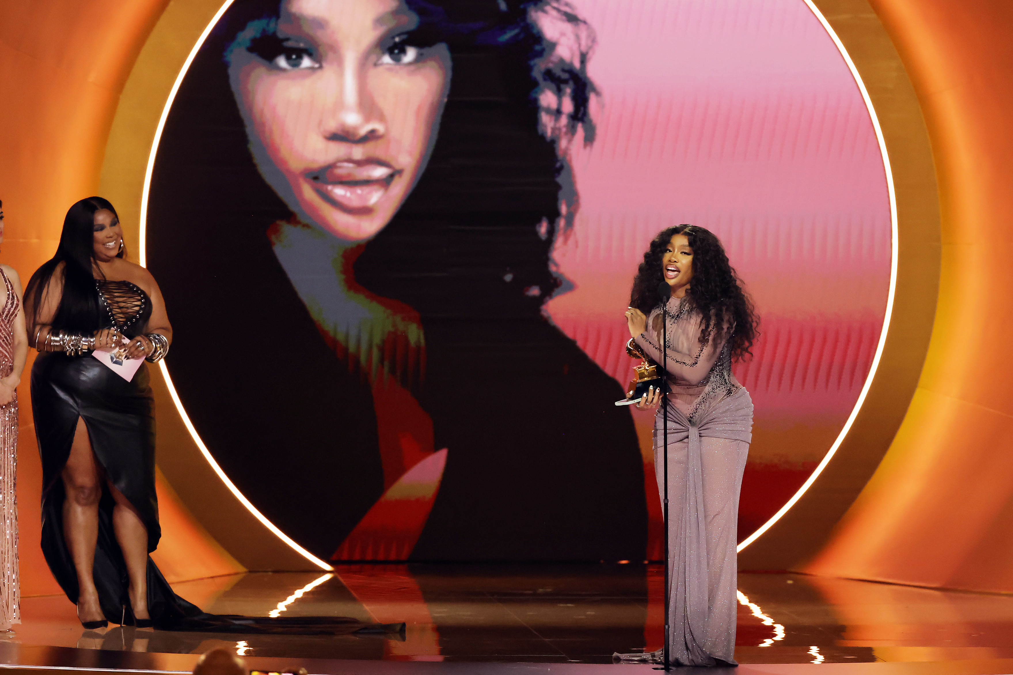 Lizzo and SZA onstage as SZA accepts her Grammy