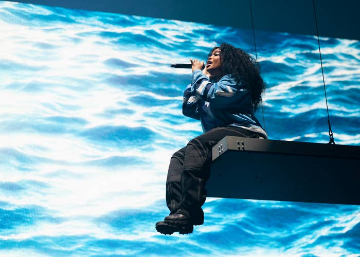 SZA sitting on a platform suspended in the air as she performs