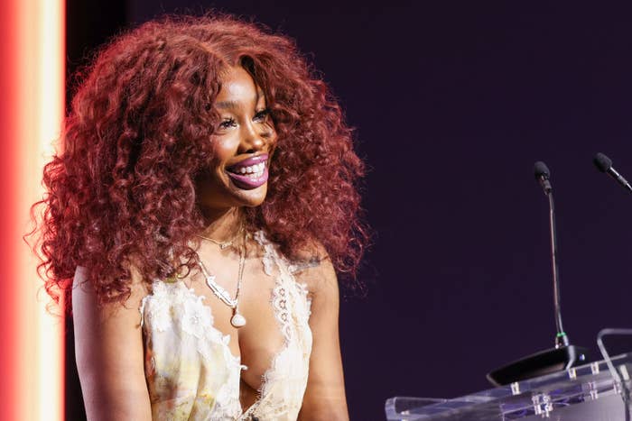 SZA smiling while standing at podium