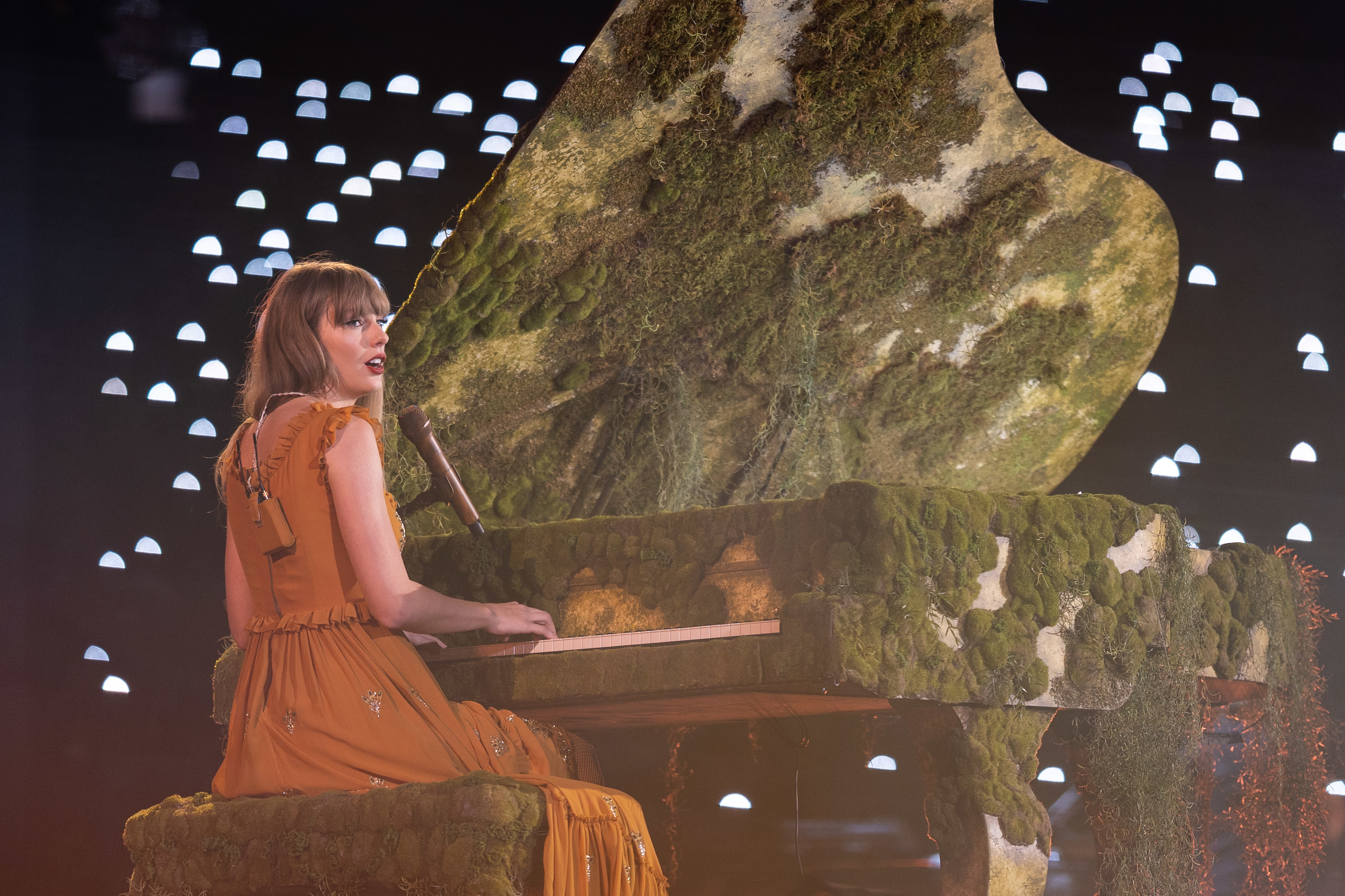 Taylor Swift onstage at a moss-covered piano