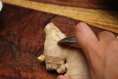 Someone peeling ginger with a spoon