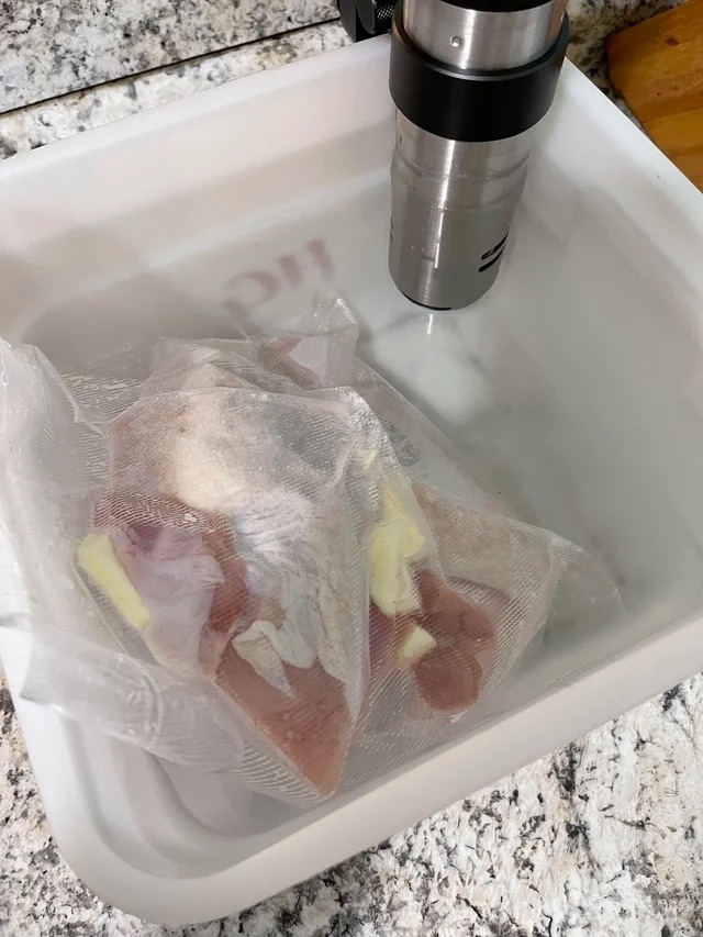 Vacuum-sealed turkey breasts in a sous vide water bath