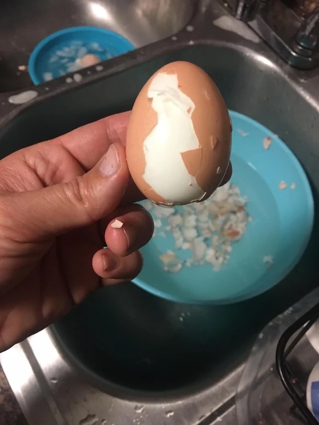 Someone holding a hard-boiled egg that has been partially peeled
