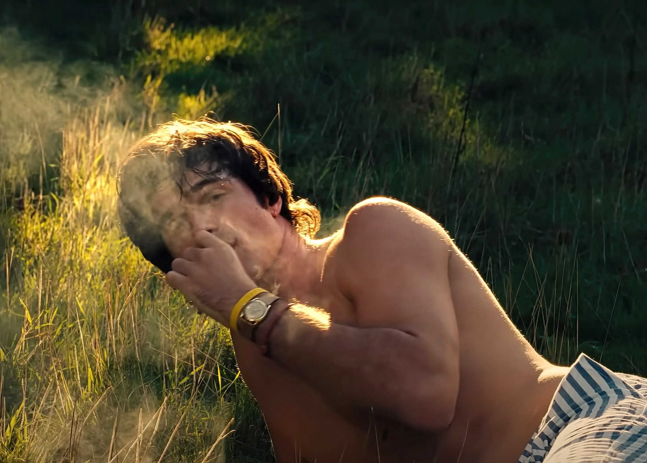 Jacob&#x27;s character smoking why lying in the grass in a scene from &quot;Saltburn&quot;