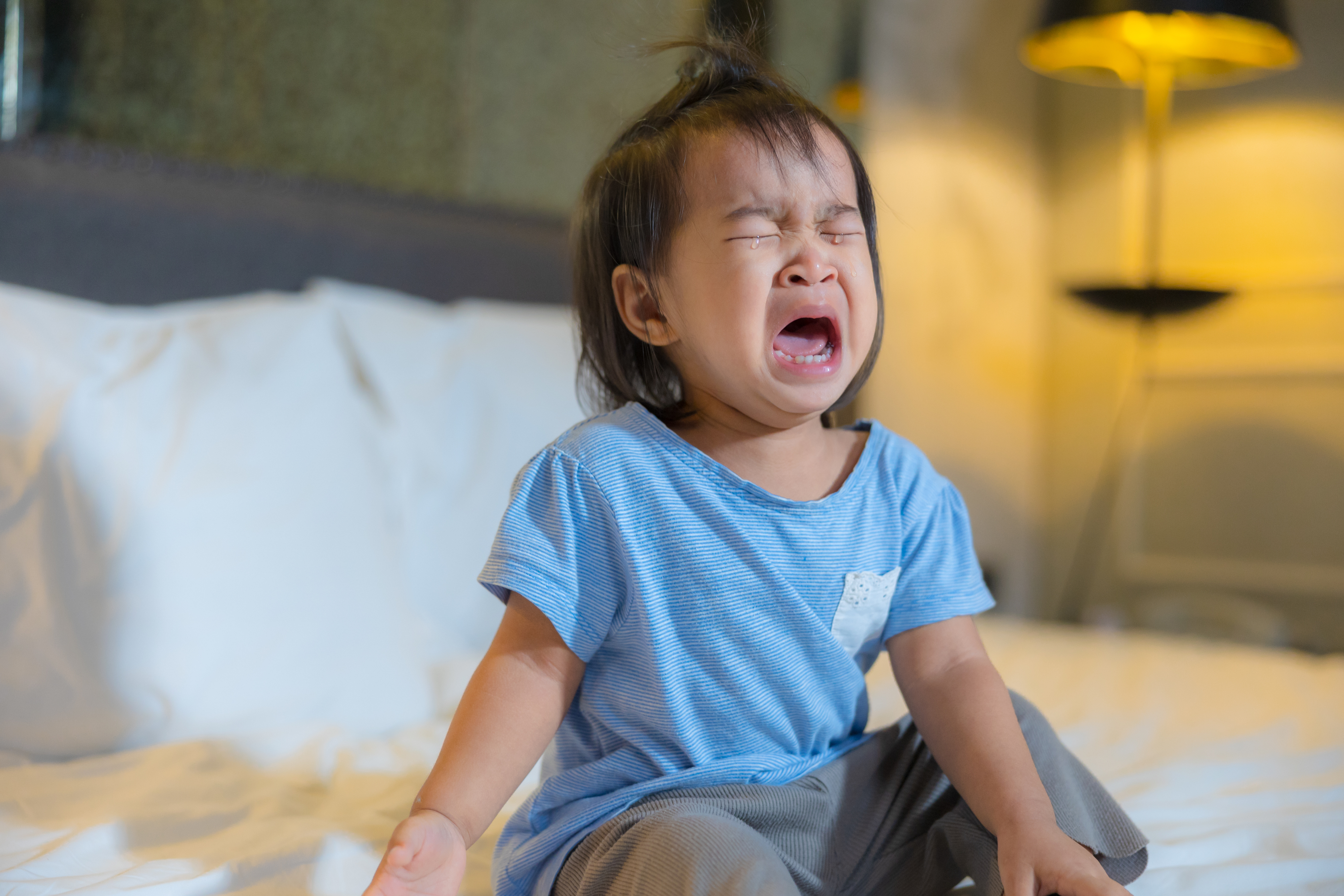 a toddler crying on her bed